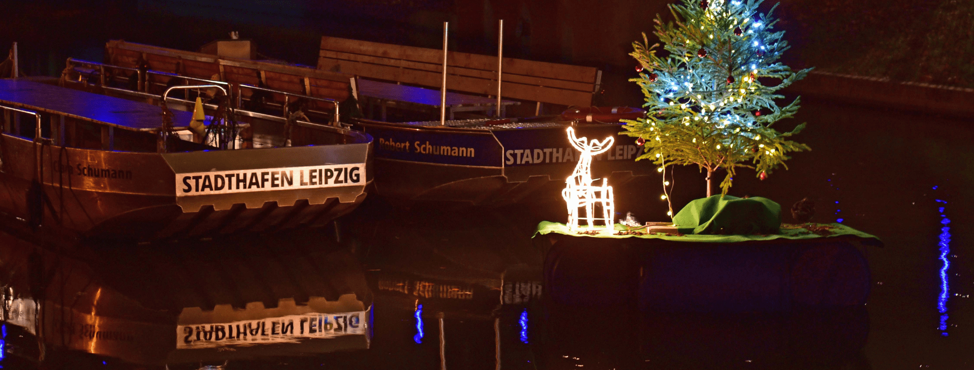 Zwei Motorboote werden von der Weihnachtsbeleuchtung angeleuchtet.